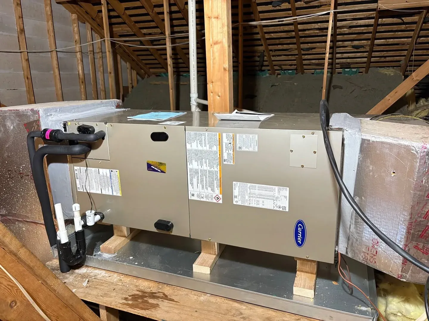 New Carrier horizontal air handler installed on a raised platform in a residential attic